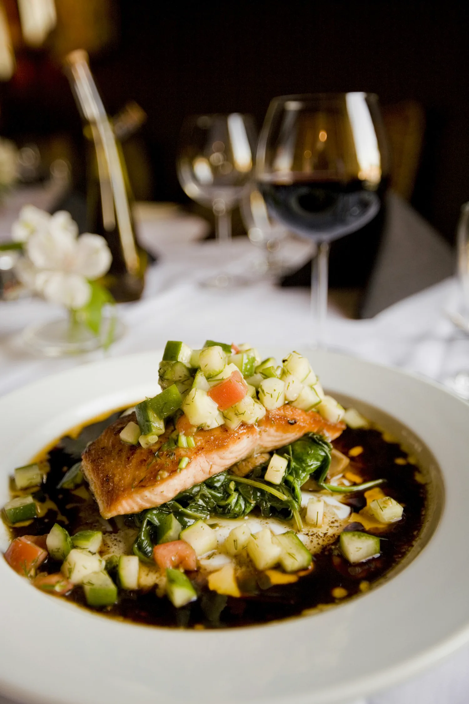 A composed dish plated on a white plate under low warm restaurant light