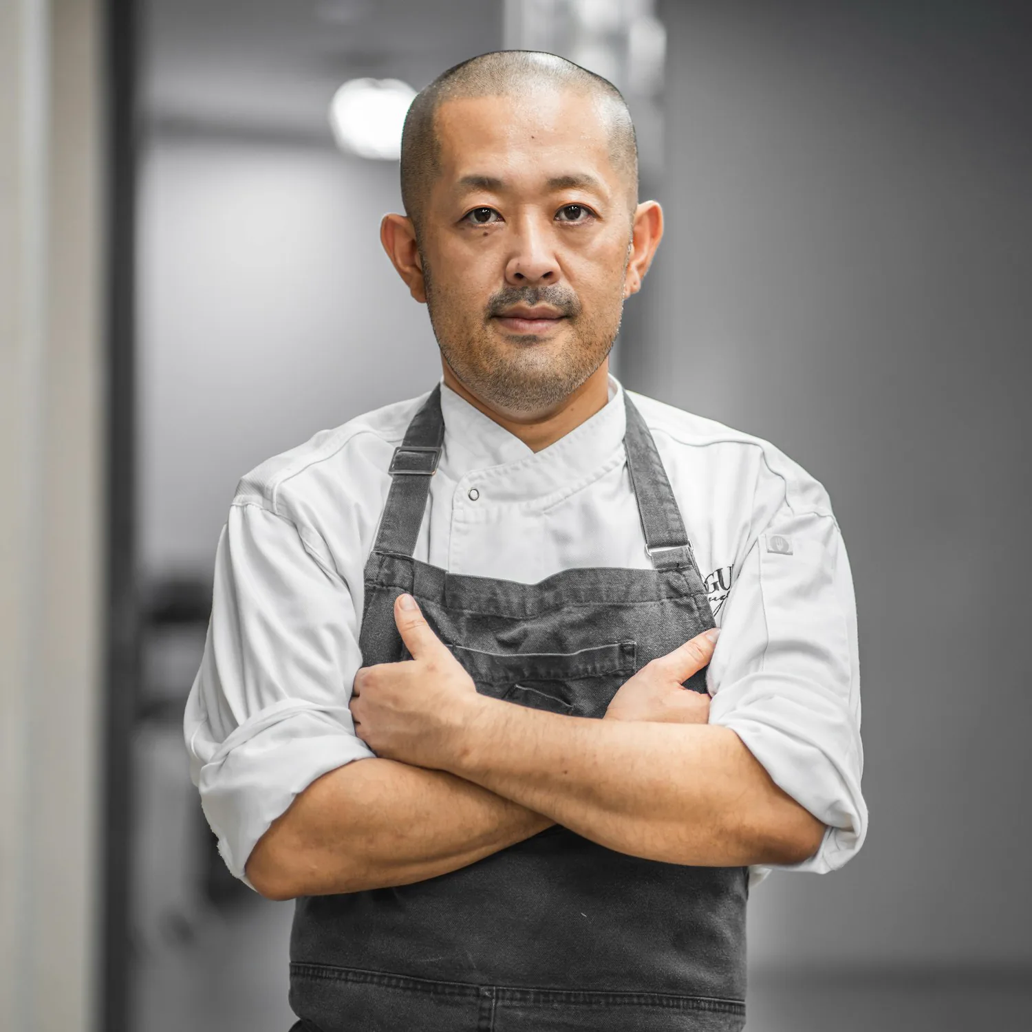 A chef working over a pan as a tall flame flares up in a professional kitchen
