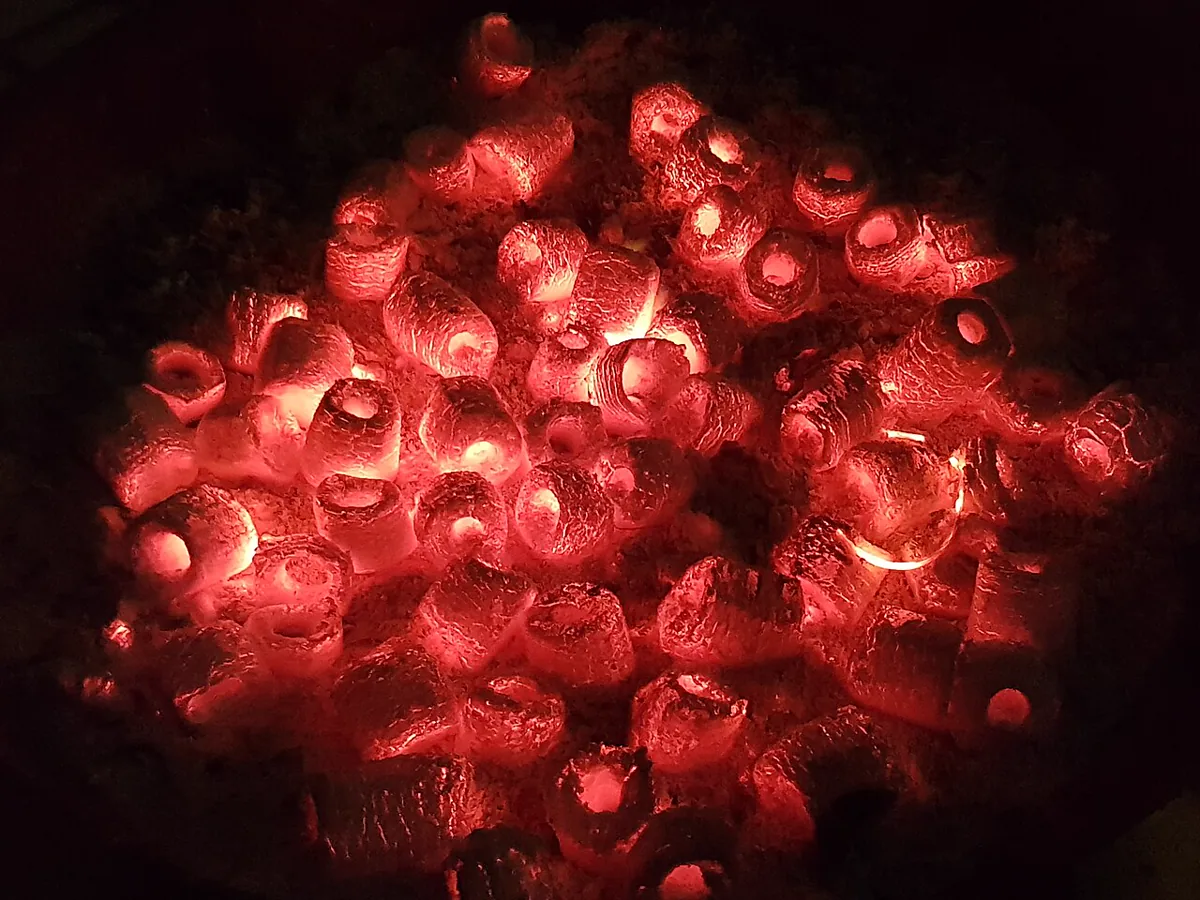 Hot black coals glowing orange in a barbecue