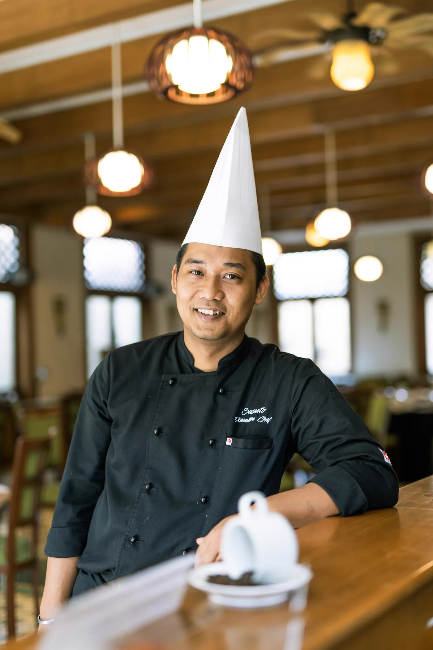 A chef in white chef's whites, arms crossed, photographed against a plain background